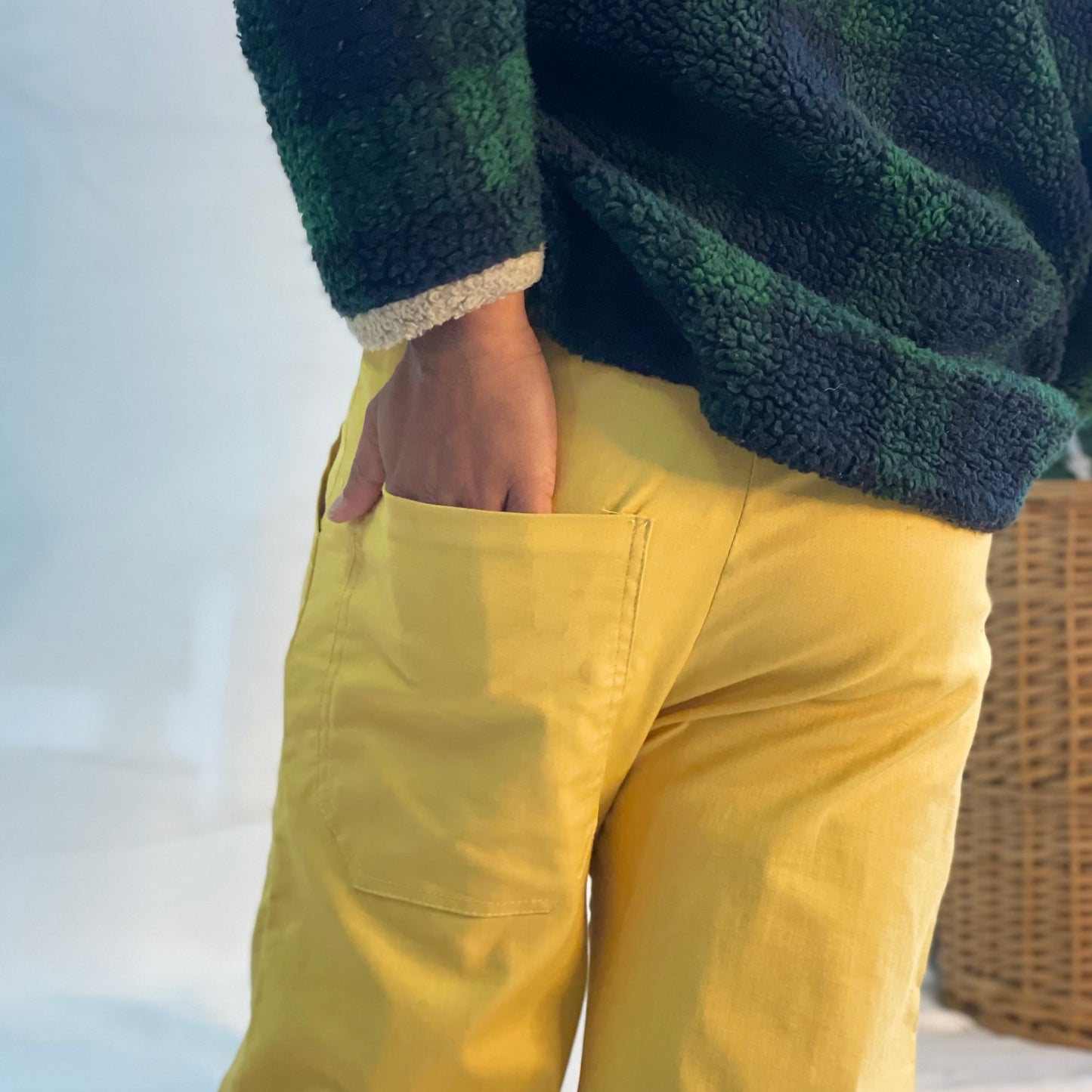 Model wearing mustard coloured pants with a wool plaid jersey against a white backdrop.