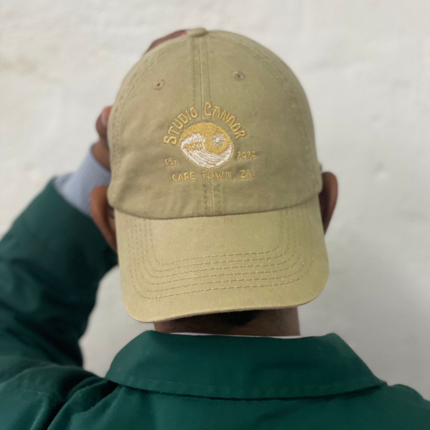 Model wears stone coloured cap backwards.