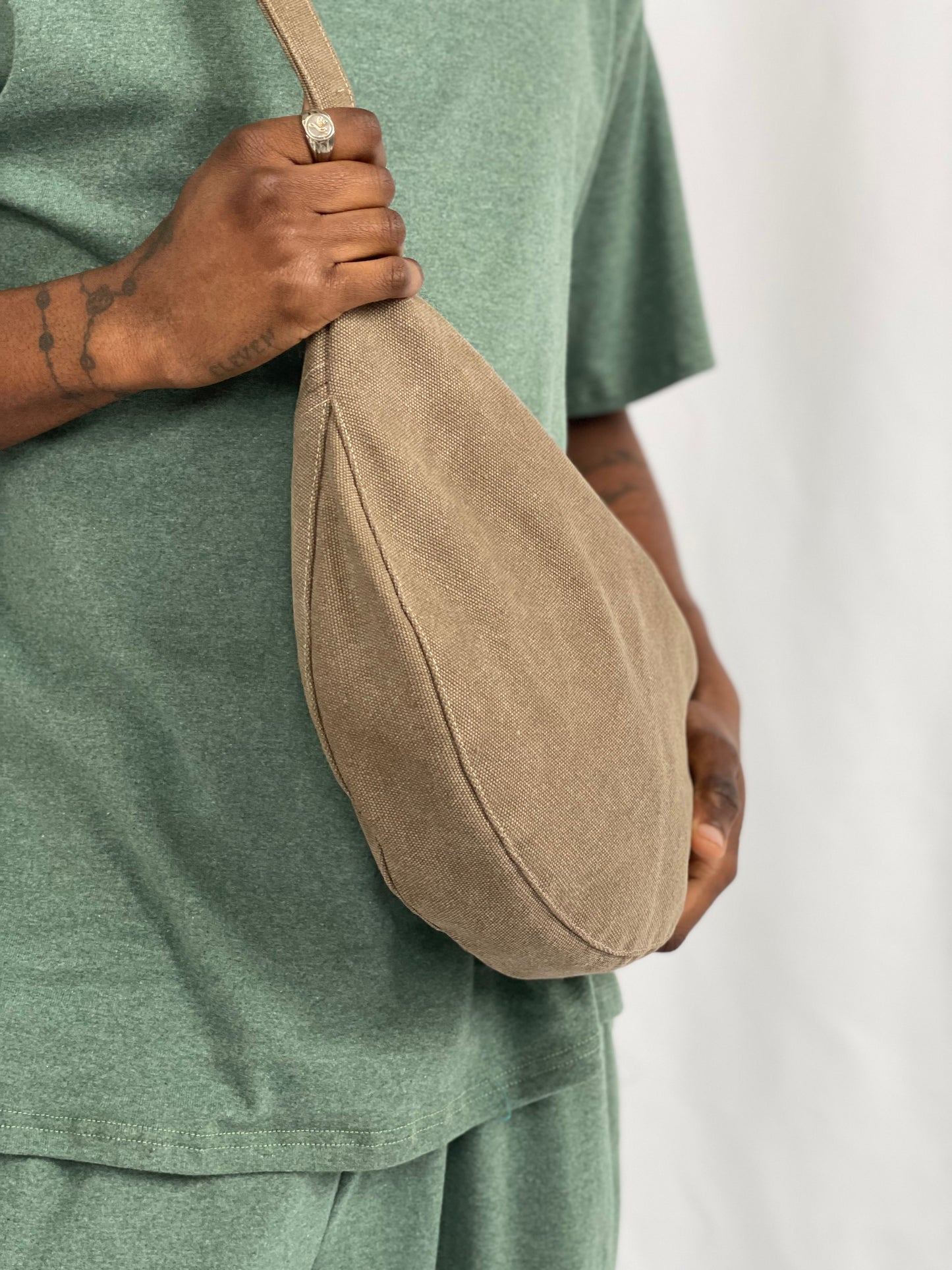 Close up of model wearing brown sling bag and green top and pants.