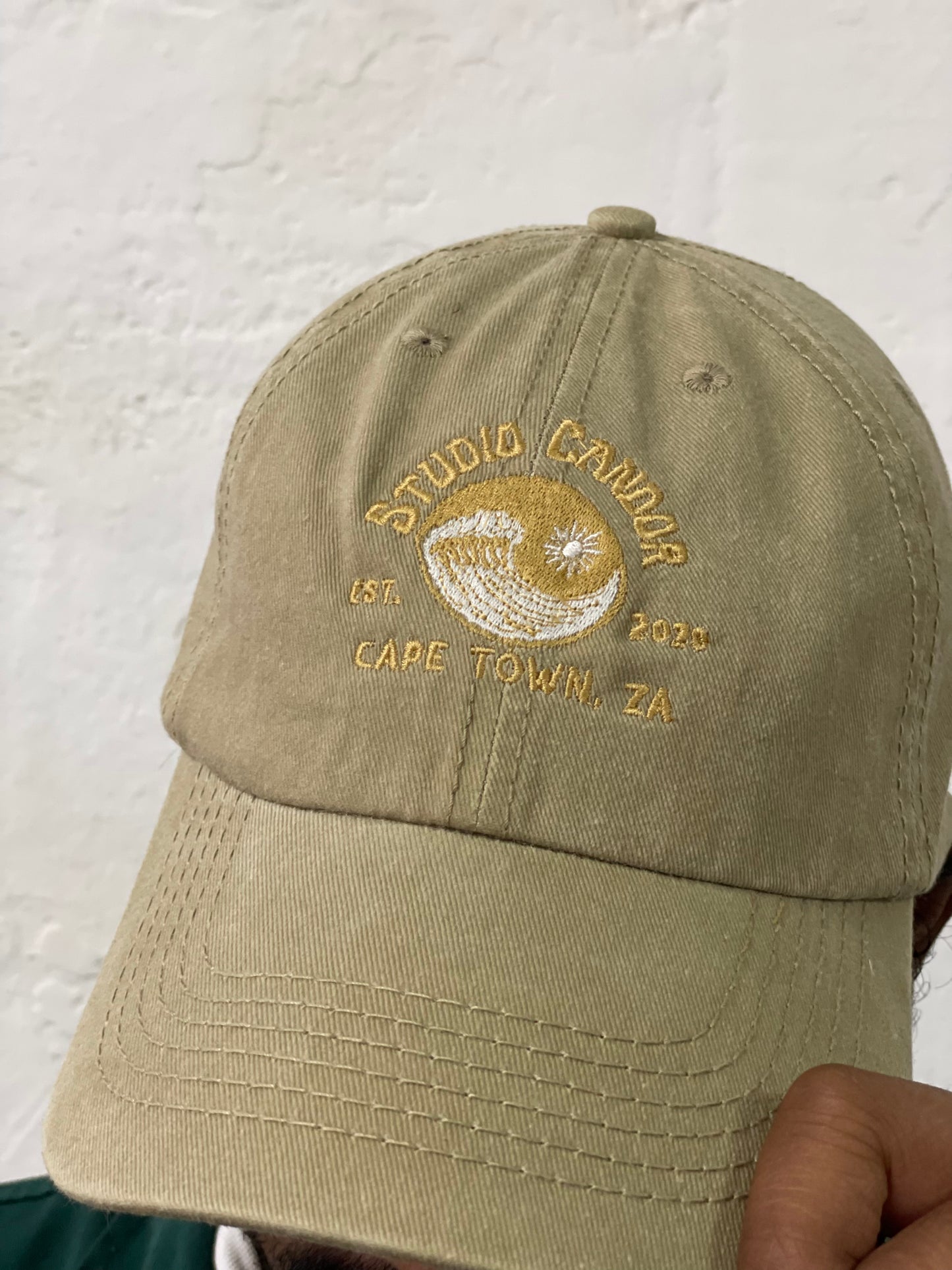 Model holds the corner of stone coloured peak cap.