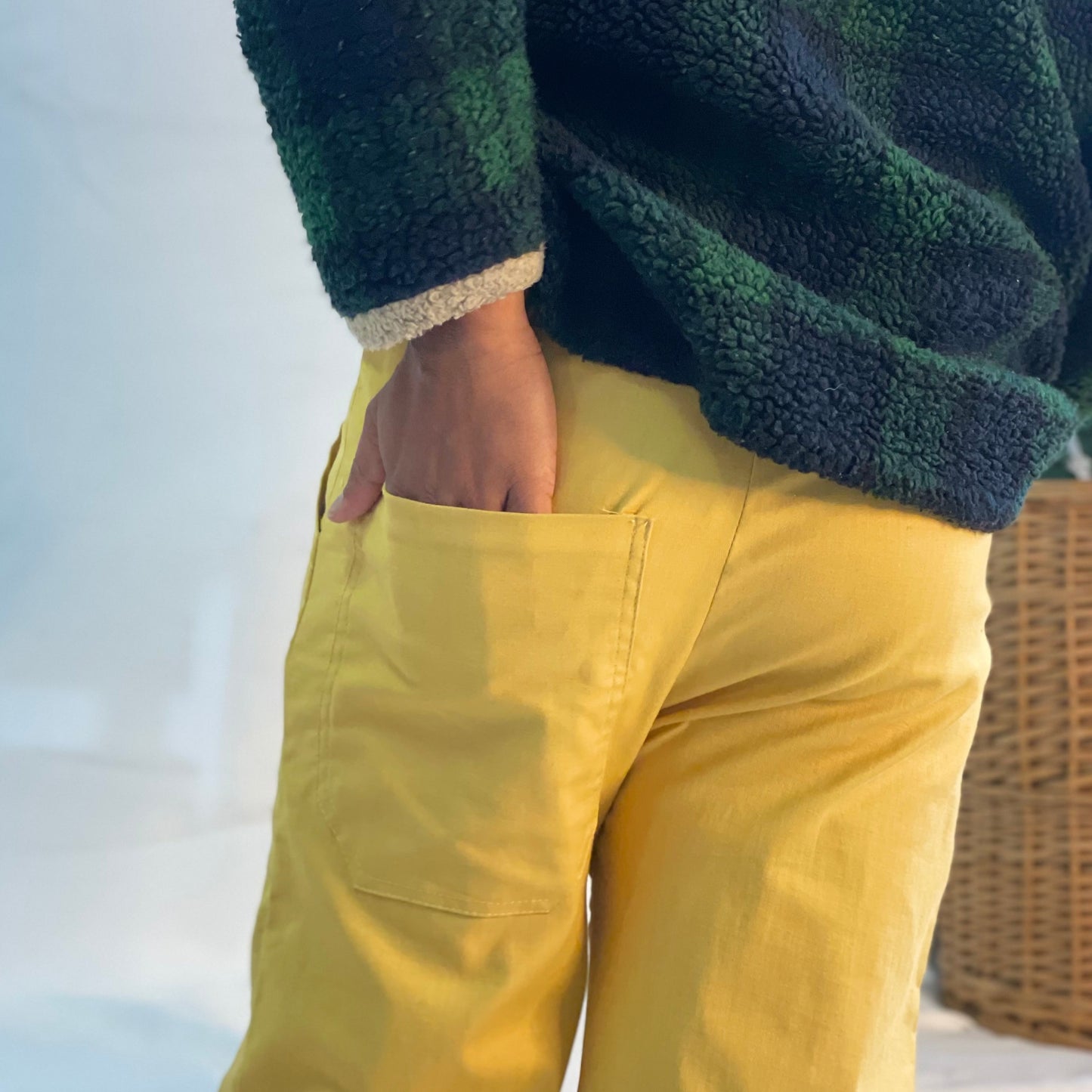 Model wearing mustard coloured pants with a wool plaid jersey against a white backdrop. 