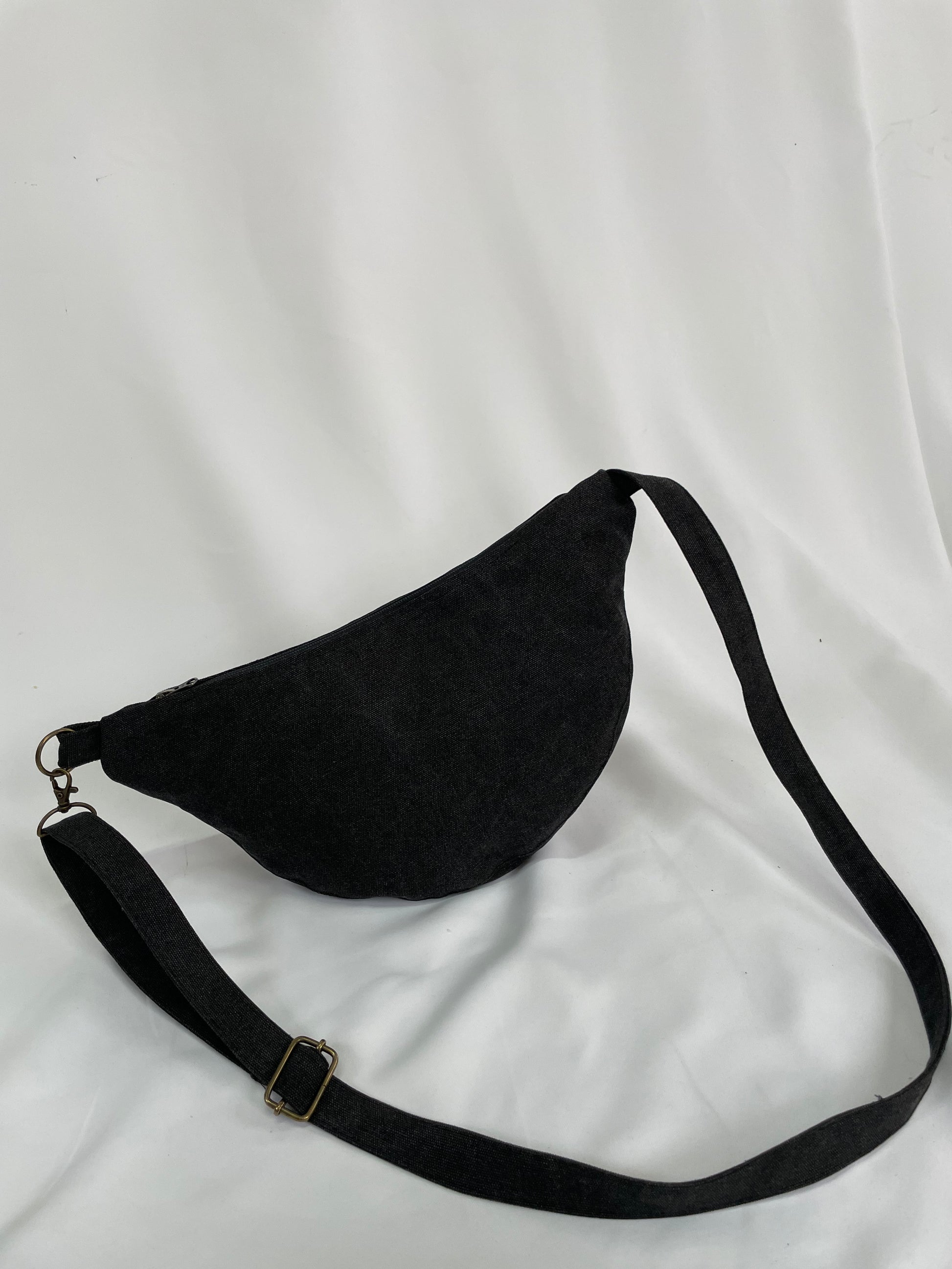 Black sling bag with topstitching, brass hardware and YKK zips