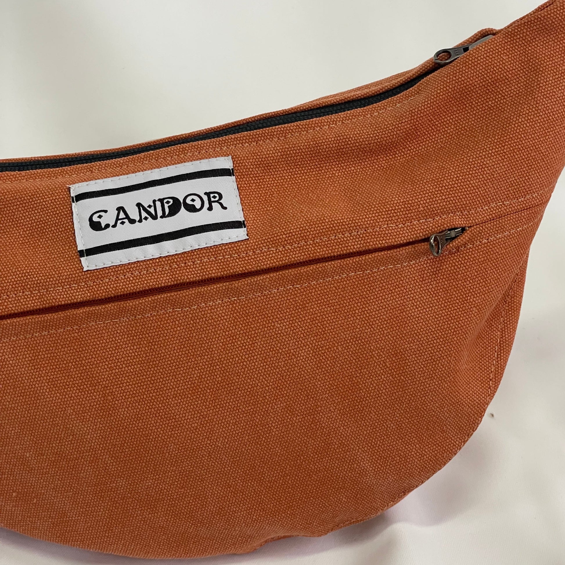 Close up of orange sling bag with top stitching and YKK zips