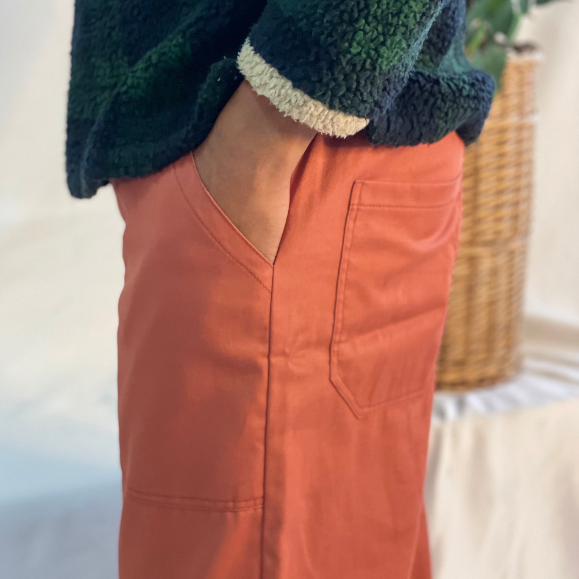 Model wearing rust coloured pants with a wool plaid jersey against a white backdrop.