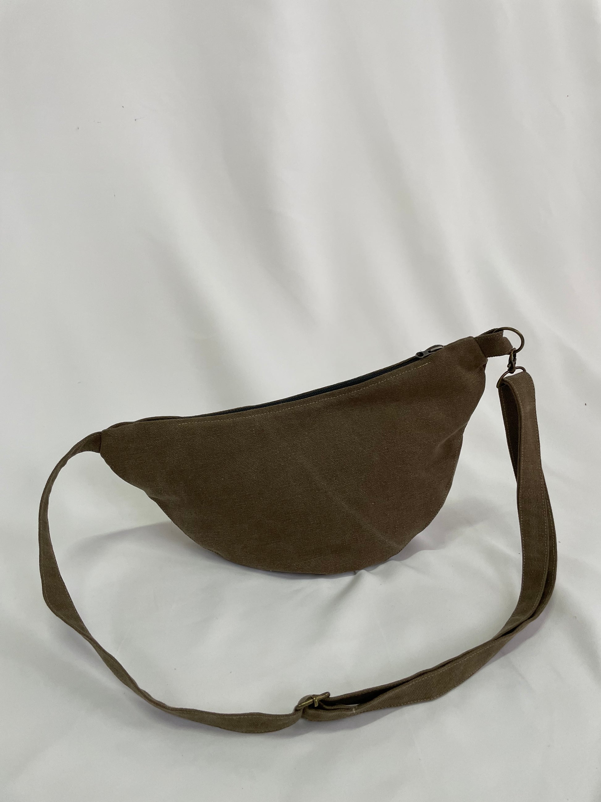 Brown sling bag with topstitching, brass hardware and YKK zips,