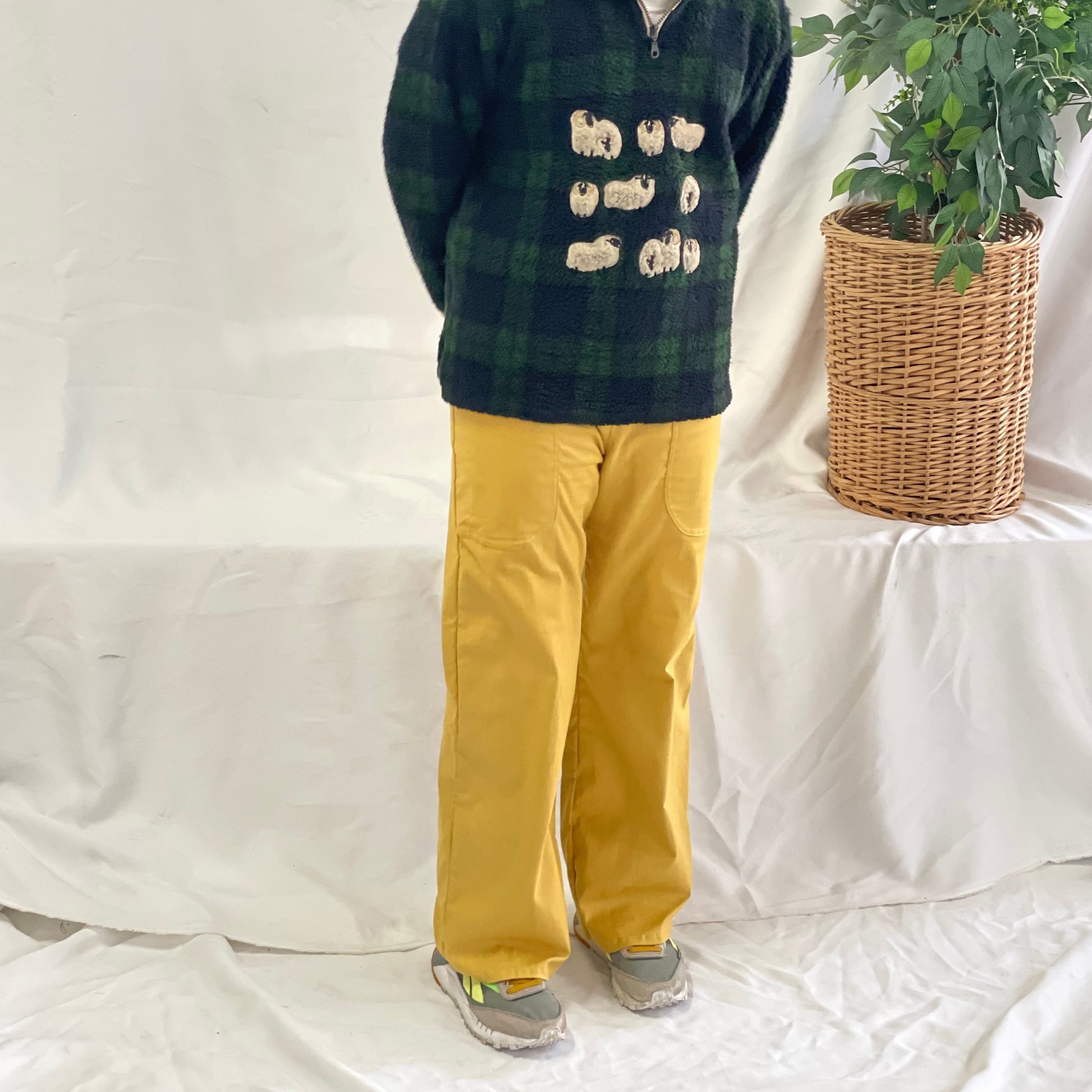 Model wearing mustard coloured pants with a wool plaid jersey against a white backdrop. 